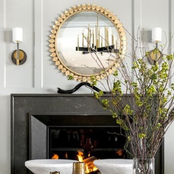 Gold sunburst mirror over black marble fireplace mantel