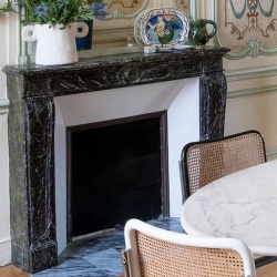 The black marble mantel props up a playful modern vase